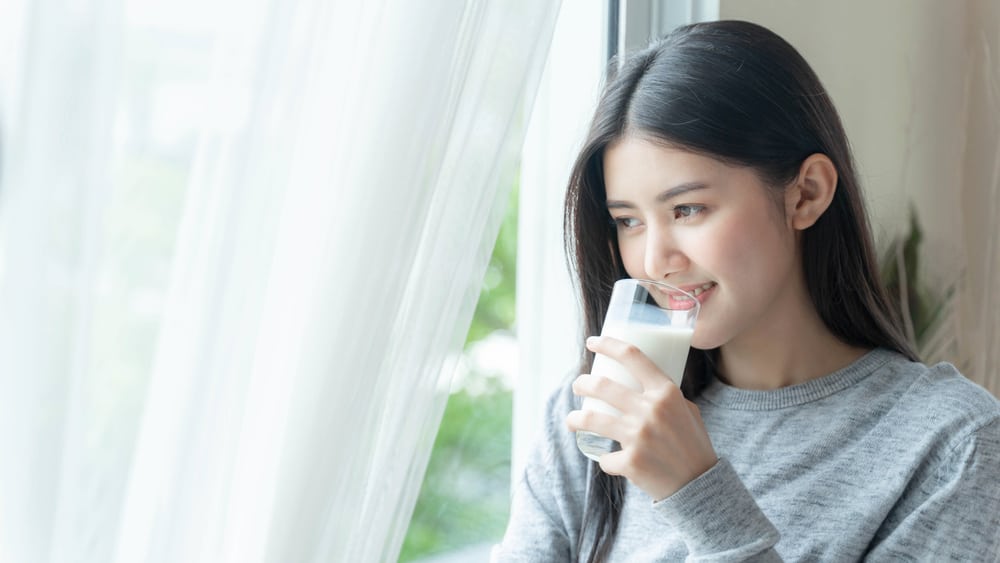 靠著窗的女人正在飲用豆漿